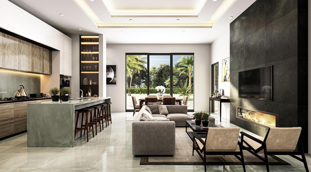 living room featuring sink, a fireplace, and a tray ceiling