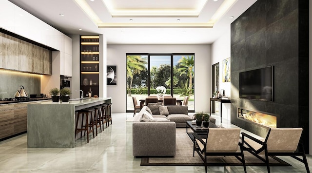 living room featuring sink, a fireplace, and a tray ceiling