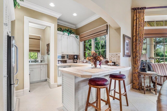 kitchen with a kitchen breakfast bar, decorative backsplash, light tile patterned floors, appliances with stainless steel finishes, and kitchen peninsula