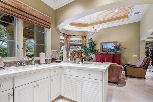 kitchen with white cabinets, hanging light fixtures, ornamental molding, and sink