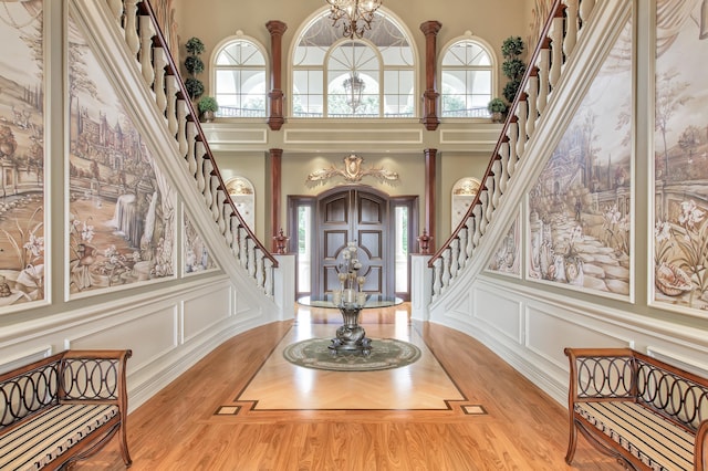 foyer entrance with decorative columns, a towering ceiling, and a notable chandelier