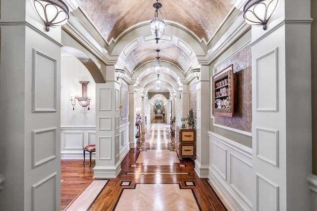 hall featuring decorative columns, vaulted ceiling, and ornamental molding