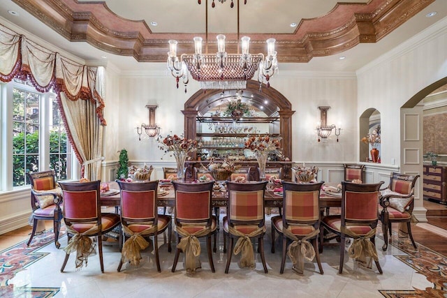 bar with a raised ceiling, hanging light fixtures, crown molding, and a notable chandelier