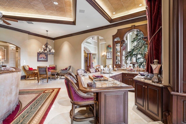 bar featuring a raised ceiling, light stone counters, crown molding, pendant lighting, and ceiling fan with notable chandelier