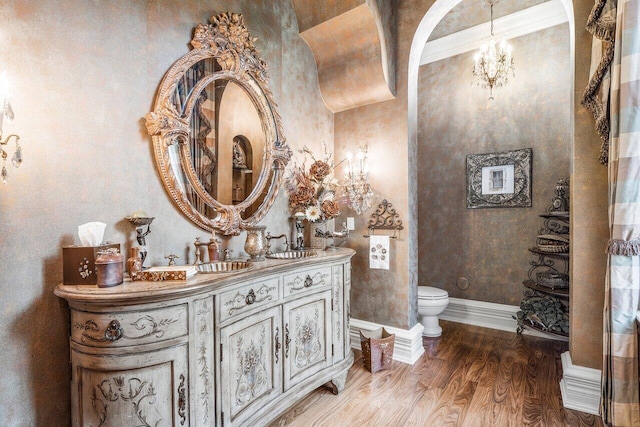 bathroom featuring vanity, toilet, wood-type flooring, and ornamental molding