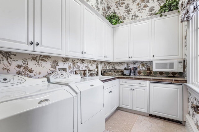 clothes washing area with washer and dryer, cabinets, light tile patterned floors, and sink