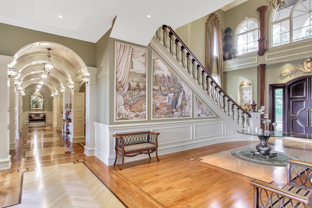 entrance foyer featuring ornate columns, light parquet floors, and ornamental molding