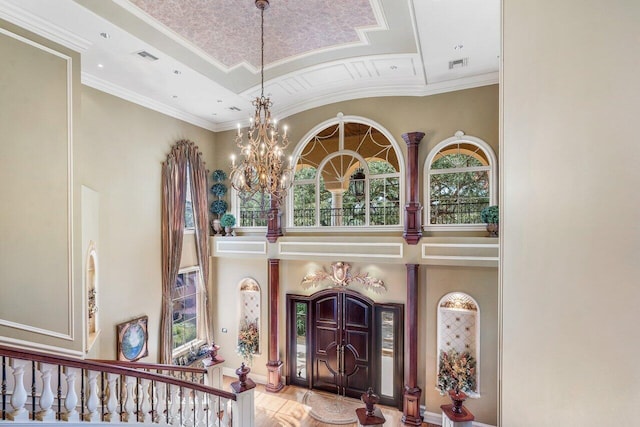 entrance foyer with a chandelier, high vaulted ceiling, and crown molding