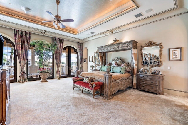 bedroom with french doors, a tray ceiling, and multiple windows