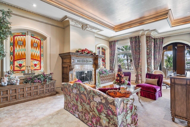 carpeted living room featuring a raised ceiling, ornamental molding, and a high end fireplace