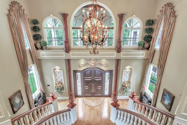 foyer with hardwood / wood-style floors, a healthy amount of sunlight, a high ceiling, and an inviting chandelier