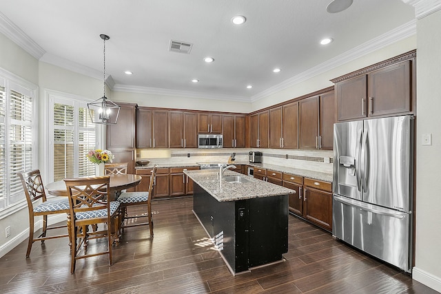 kitchen with light stone countertops, sink, an island with sink, pendant lighting, and appliances with stainless steel finishes