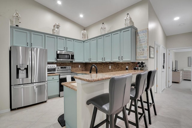kitchen featuring light tile patterned floors, decorative backsplash, blue cabinetry, and appliances with stainless steel finishes