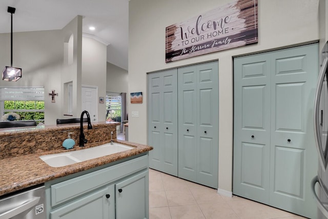 kitchen with pendant lighting, sink, high vaulted ceiling, stone countertops, and stainless steel dishwasher