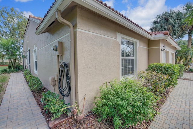 view of property exterior with a tile roof and stucco siding