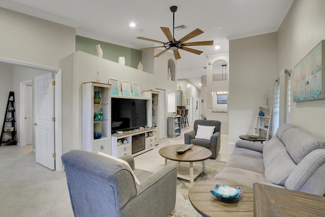 tiled living room with a towering ceiling, ornamental molding, and ceiling fan