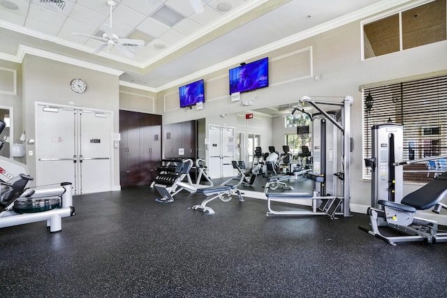 workout area with baseboards, visible vents, a ceiling fan, a high ceiling, and crown molding