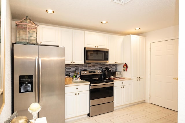 kitchen with decorative backsplash, stainless steel appliances, and white cabinetry