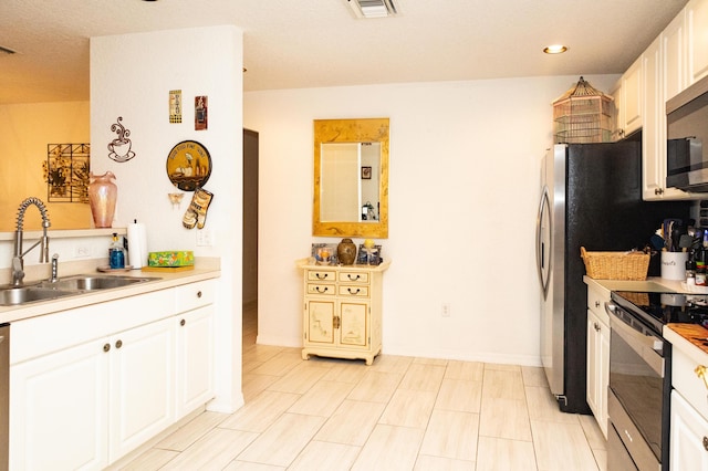 kitchen featuring white cabinets, appliances with stainless steel finishes, and sink