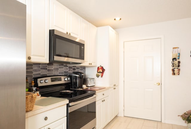 kitchen featuring backsplash, white cabinetry, light tile patterned floors, and stainless steel appliances