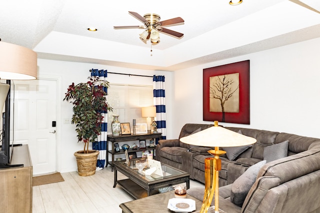 living room with a raised ceiling and ceiling fan