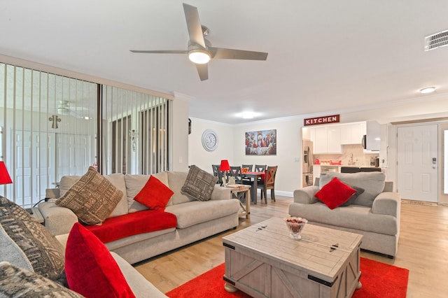 living room featuring ceiling fan, sink, light wood-type flooring, and ornamental molding