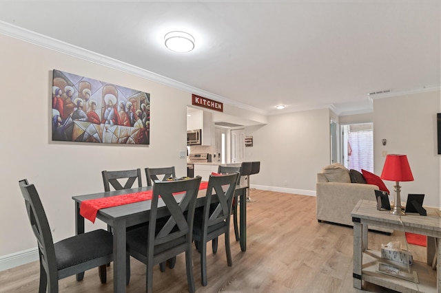 dining room with light hardwood / wood-style flooring and crown molding