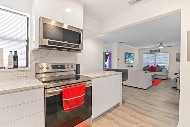 kitchen featuring backsplash, ceiling fan, white cabinets, and stainless steel appliances