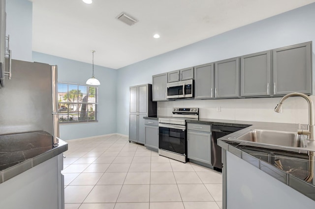 kitchen with gray cabinetry, pendant lighting, light tile patterned floors, and appliances with stainless steel finishes