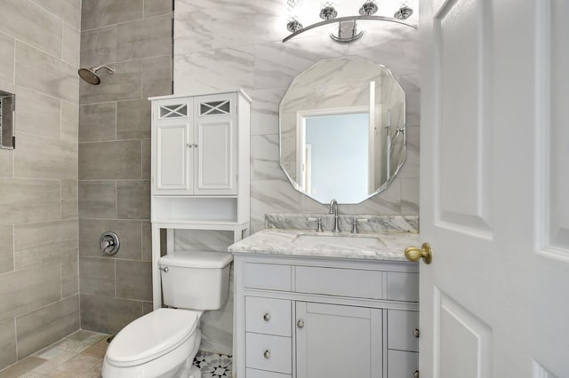 bathroom with vanity, toilet, and tiled shower