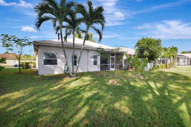 8620 Pine Cay, West Palm Beach, FL 33411 - back of property featuring a yard, stucco siding, a sunroom, and a tile roof