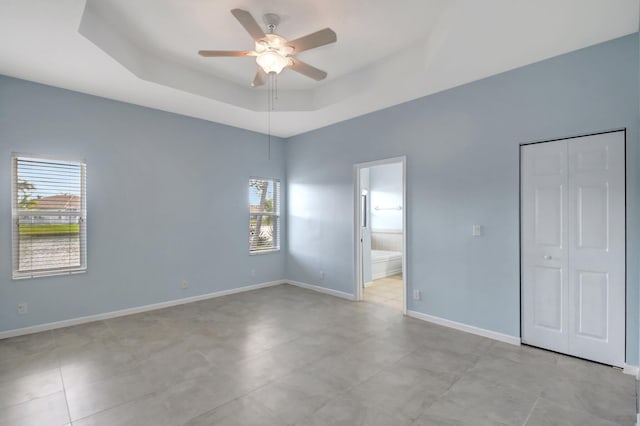 spare room with a tray ceiling and ceiling fan