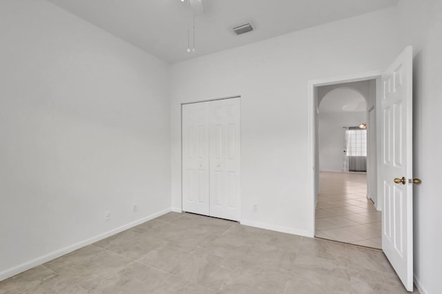 8620 Pine Cay, West Palm Beach, FL 33411 - unfurnished bedroom with arched walkways, light tile patterned floors, baseboards, a closet, and ceiling fan