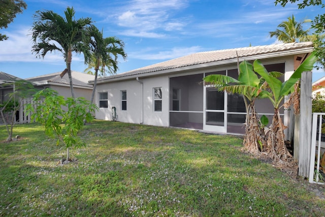 back of property featuring a sunroom and a lawn