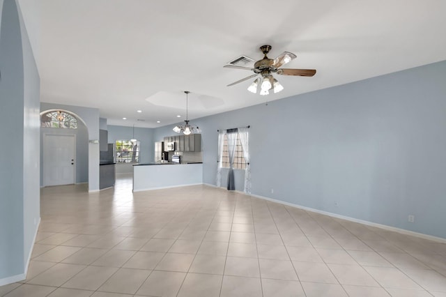 unfurnished living room featuring plenty of natural light, light tile patterned floors, and ceiling fan with notable chandelier