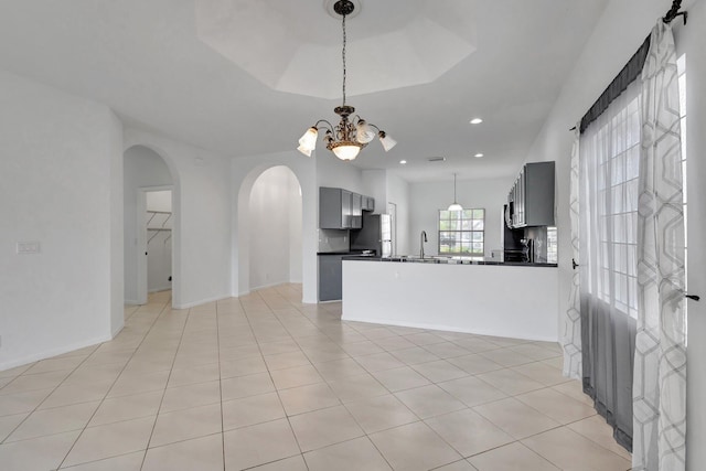 8620 Pine Cay, West Palm Beach, FL 33411 - kitchen featuring dark countertops, arched walkways, a sink, a chandelier, and pendant lighting