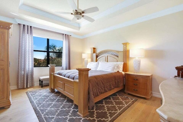 bedroom with a raised ceiling, ceiling fan, light hardwood / wood-style floors, and ornamental molding