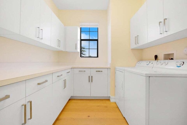 laundry room with cabinets, light hardwood / wood-style flooring, and washer and clothes dryer