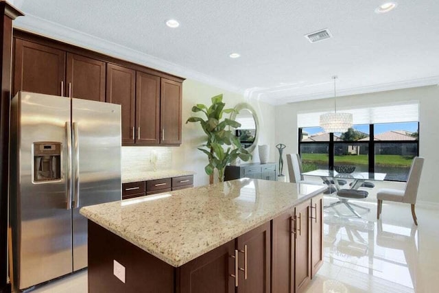 kitchen with a center island, hanging light fixtures, decorative backsplash, light stone countertops, and stainless steel fridge with ice dispenser