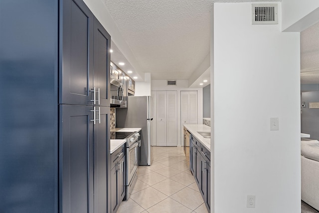 kitchen featuring stainless steel appliances, light tile patterned flooring, sink, and a textured ceiling