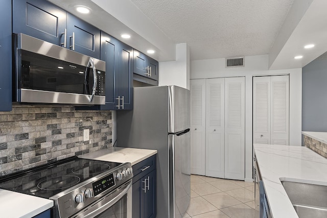 kitchen with visible vents, appliances with stainless steel finishes, decorative backsplash, blue cabinetry, and light tile patterned flooring