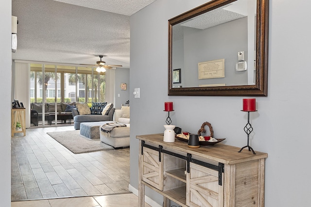 living room with ceiling fan, a textured ceiling, and light hardwood / wood-style flooring