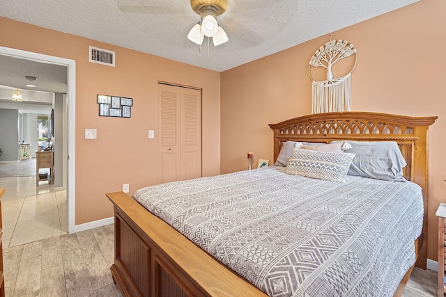 bedroom featuring ceiling fan, light hardwood / wood-style floors, a closet, and a textured ceiling