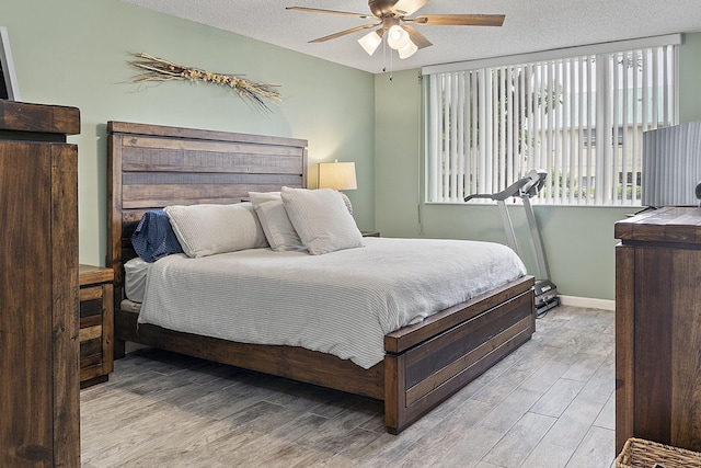 bedroom with ceiling fan, light wood-type flooring, and a textured ceiling