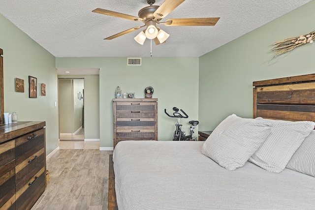 bedroom with ceiling fan, a textured ceiling, and light hardwood / wood-style flooring