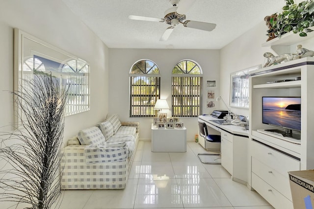 interior space featuring light tile patterned floors, a textured ceiling, a wealth of natural light, and ceiling fan