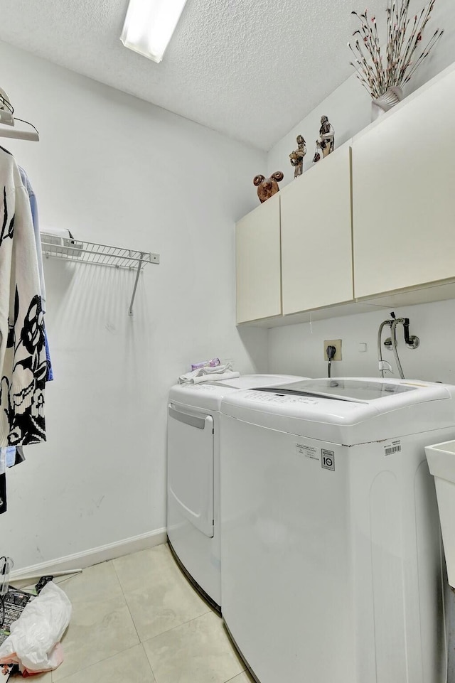 washroom featuring cabinets, light tile patterned floors, a textured ceiling, and separate washer and dryer