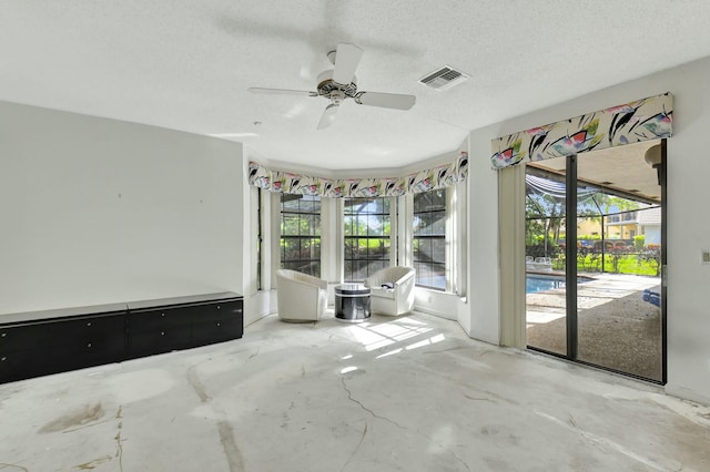 unfurnished room featuring a textured ceiling, ceiling fan, and concrete floors