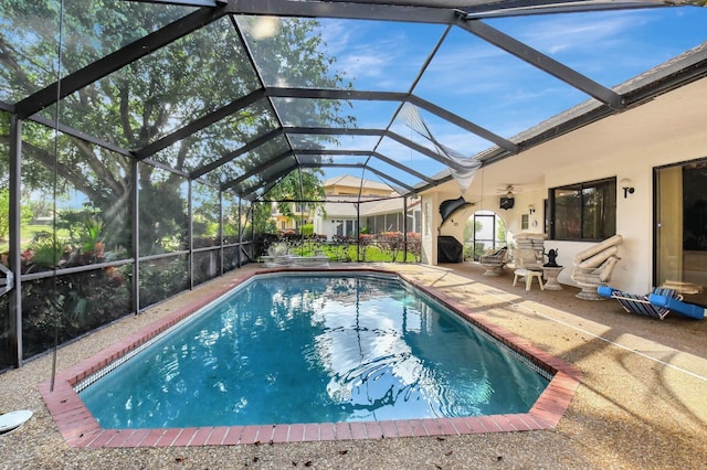 view of pool featuring glass enclosure, a patio area, and ceiling fan