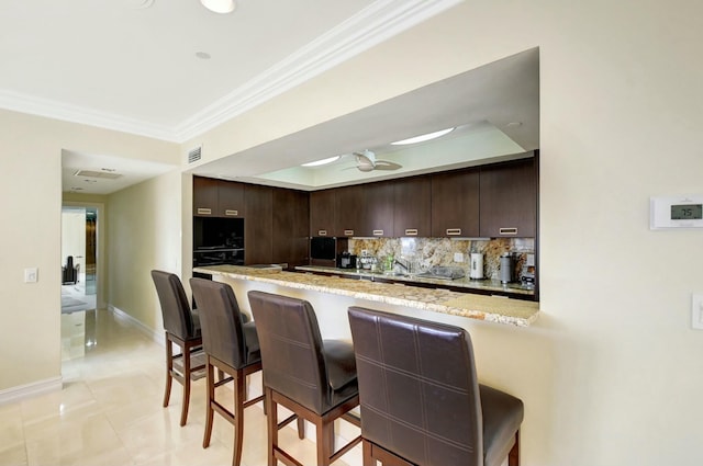 kitchen featuring a breakfast bar, kitchen peninsula, and dark brown cabinets